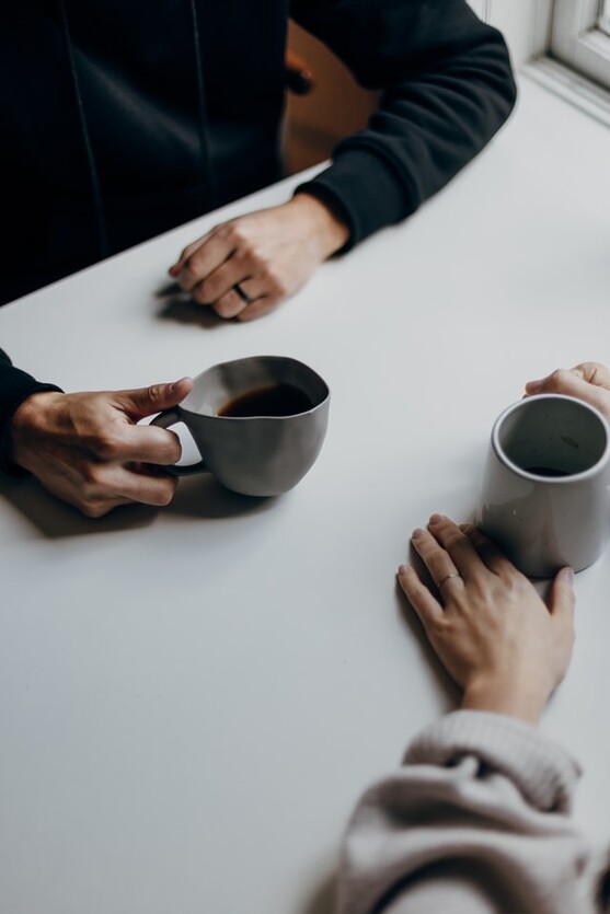 photo: two cups of coffee on a table with a man's and woman's hands near each