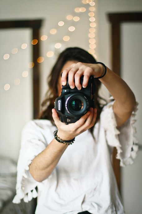 photo of a photographer pointing a camera out at the viewer obscuring her face