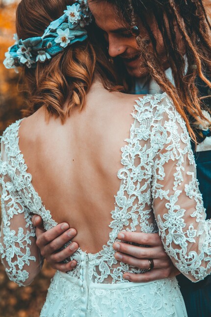 photo of groom with long dreadlocks holding bride in a white dress