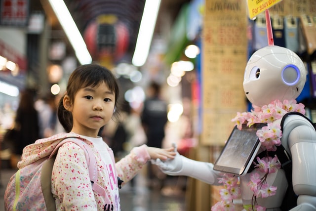 photo: little girl shakes hands with a robot in a store display