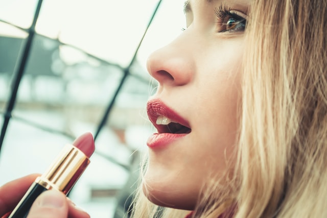 photo: young woman about to put on lipstick