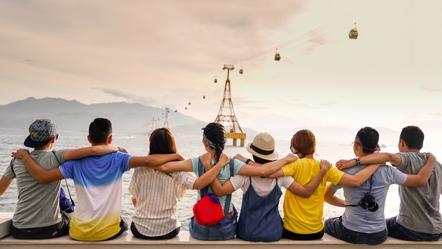 photo: kids sitting in a line with arms around each others shoulders