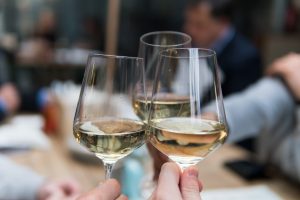 party guests toasting with wine glasses filled with white wine