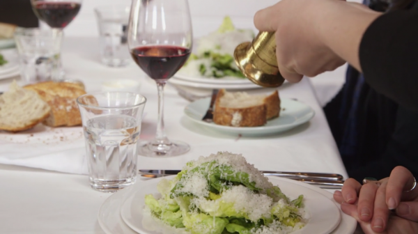 photo: server grinds pepper over salad with cheese