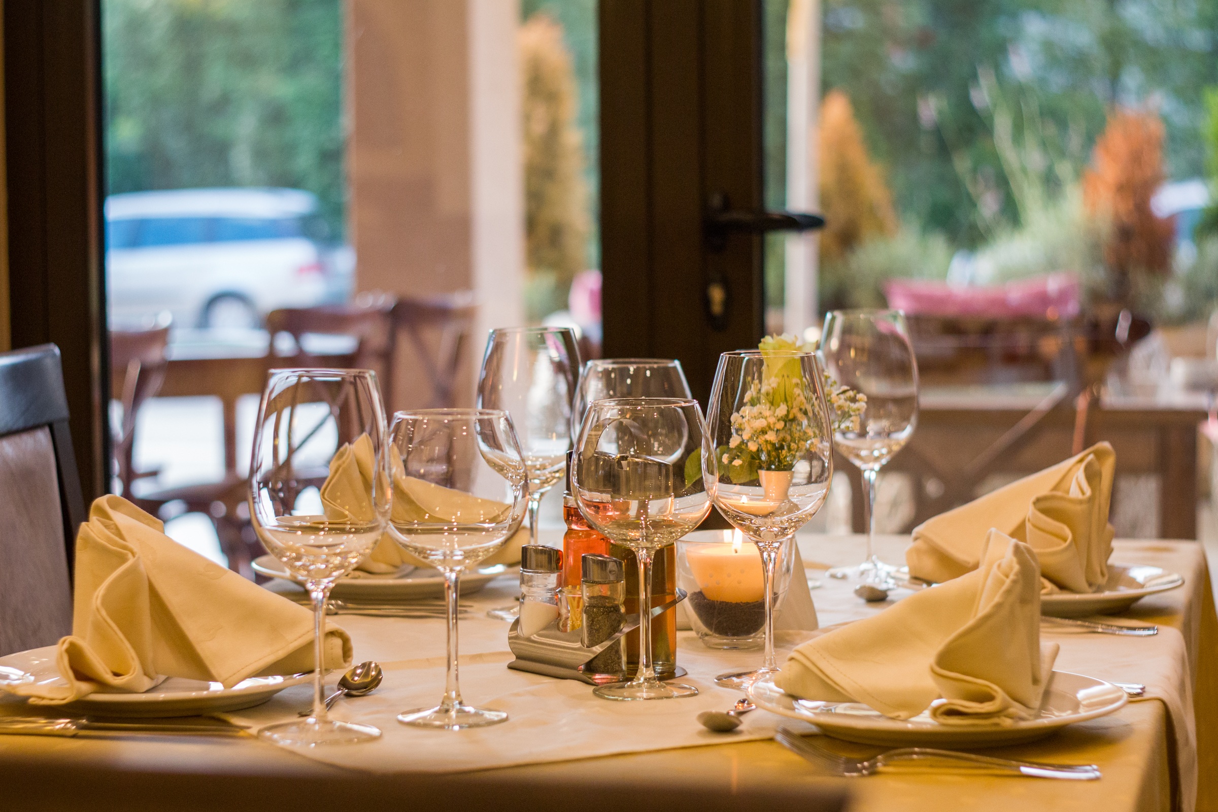 Dinner table set with white tablecloth, white plates, and wine glasses