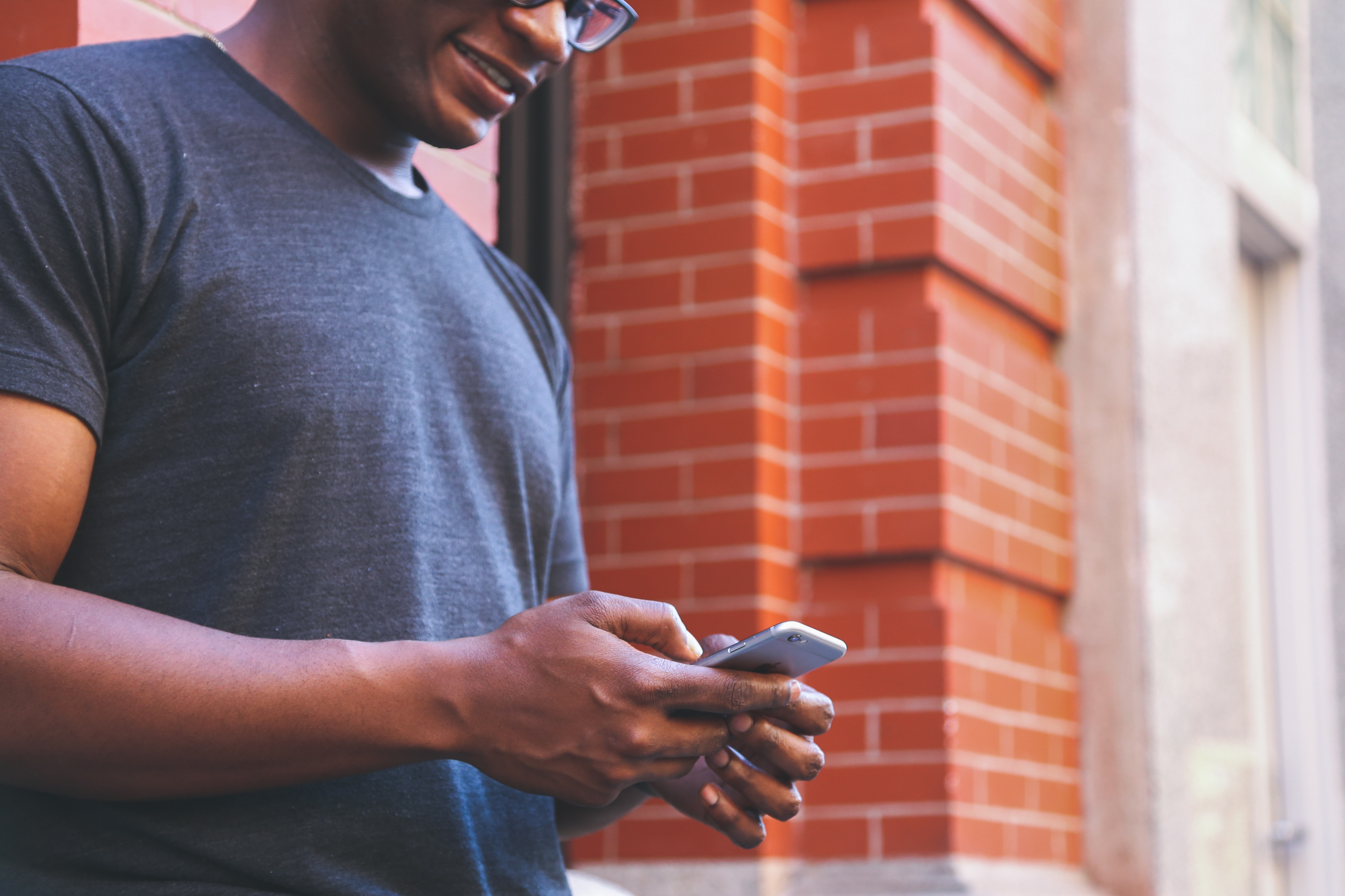 man in gray shirt texting on his phone